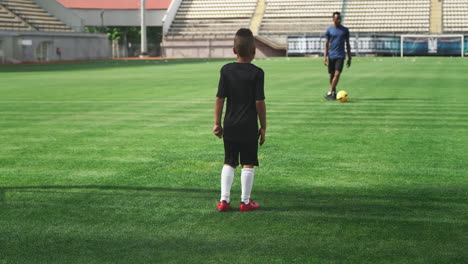 young boy practicing soccer with coach
