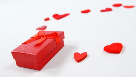 caja de regalo roja y corazones rojos en superficie blanca 4k