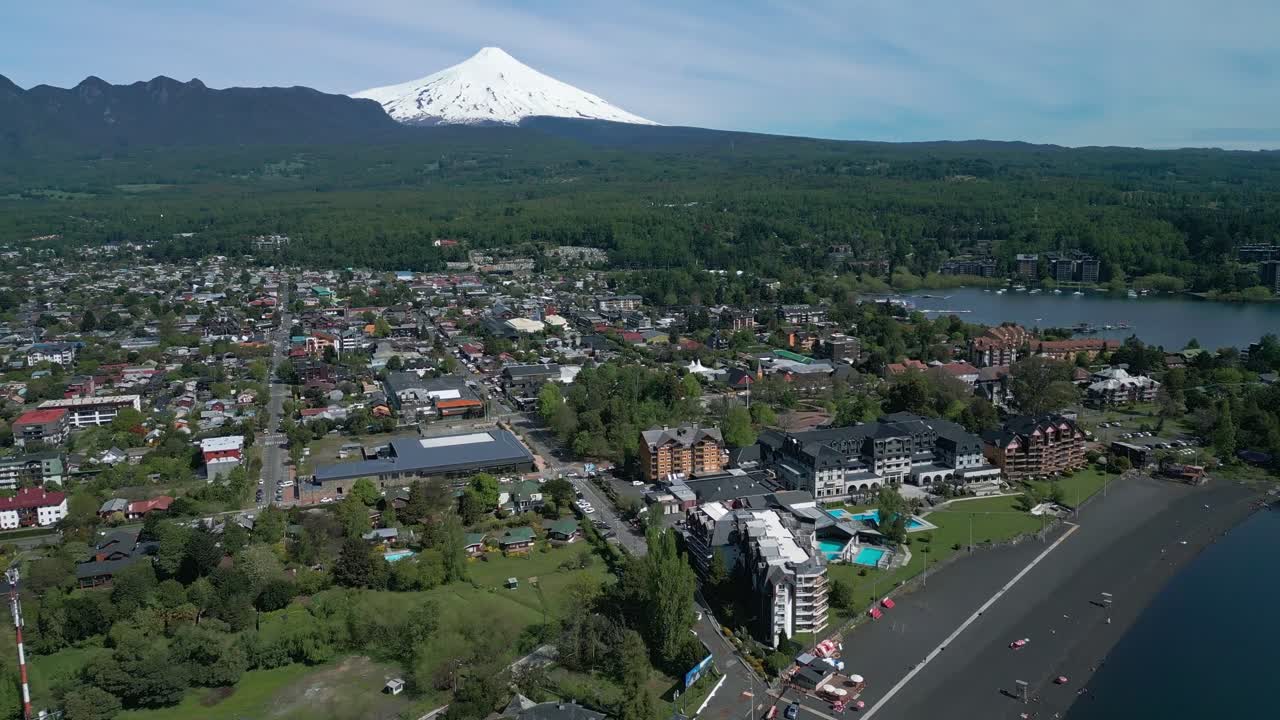Aerial view of Pucon, Chile, with black sand beach and Villarrica volcano in the background on a sunny day