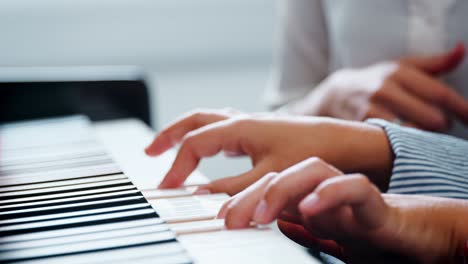 close up of pupil with teacher playing piano in music lesson