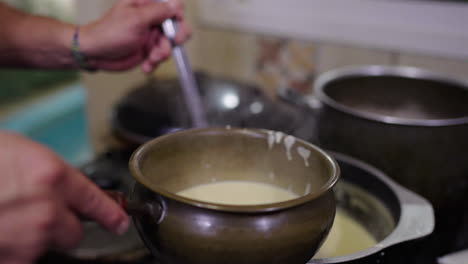 serving traditional argentine bagna cauda into bowl, creamy garlic sauce in authentic preparation