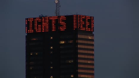 Die-Kamera-Schwenkt-Einen-Wolkenkratzer-Hoch,-Auf-Dem-Ein-Drehzelt-Steht,-Das-Die-Börse-Und-Andere-Nachrichten-Des-Tages-Ankündigt