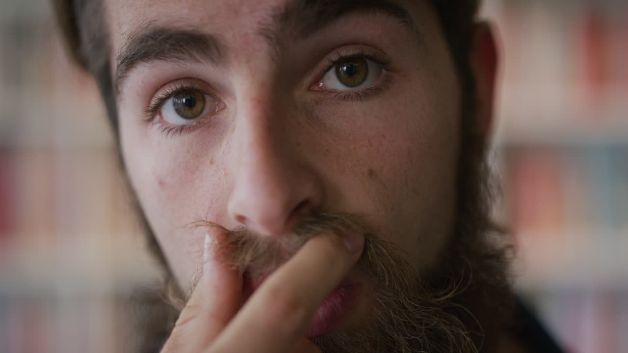 ritratto ravvicinato bell'uomo giovane hipster che tocca la barba che guarda pensieroso uomo caucasico barbuto in slow motion