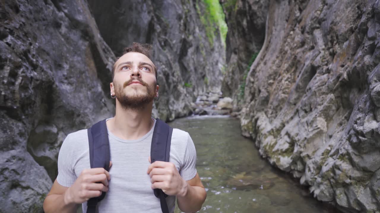Giovane uomo che ammira il canyon. C'è un torrente.