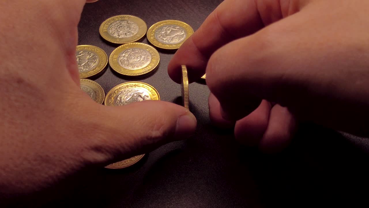 10 pesos Coin spinning by hand on a wooden table. Abundance prosperity concept