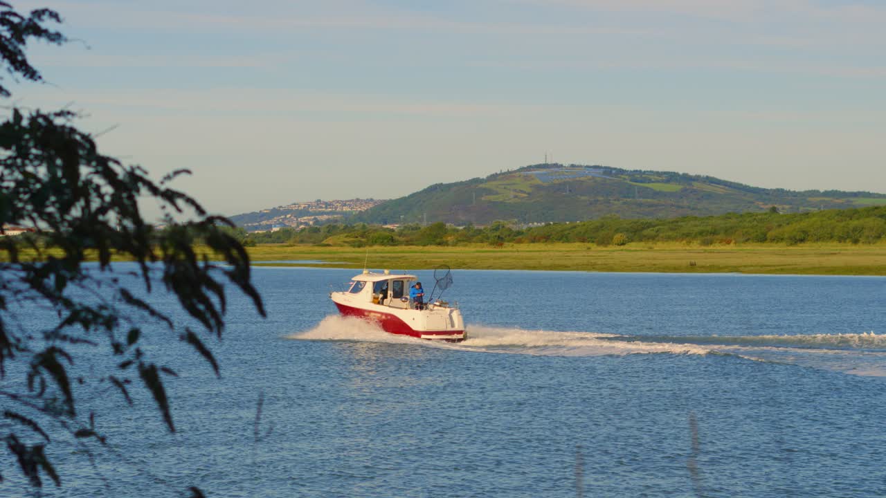 Fishing Boat Heading Out to Sea in Early Morning with Natural Hills in Background with Solar Farm on Top