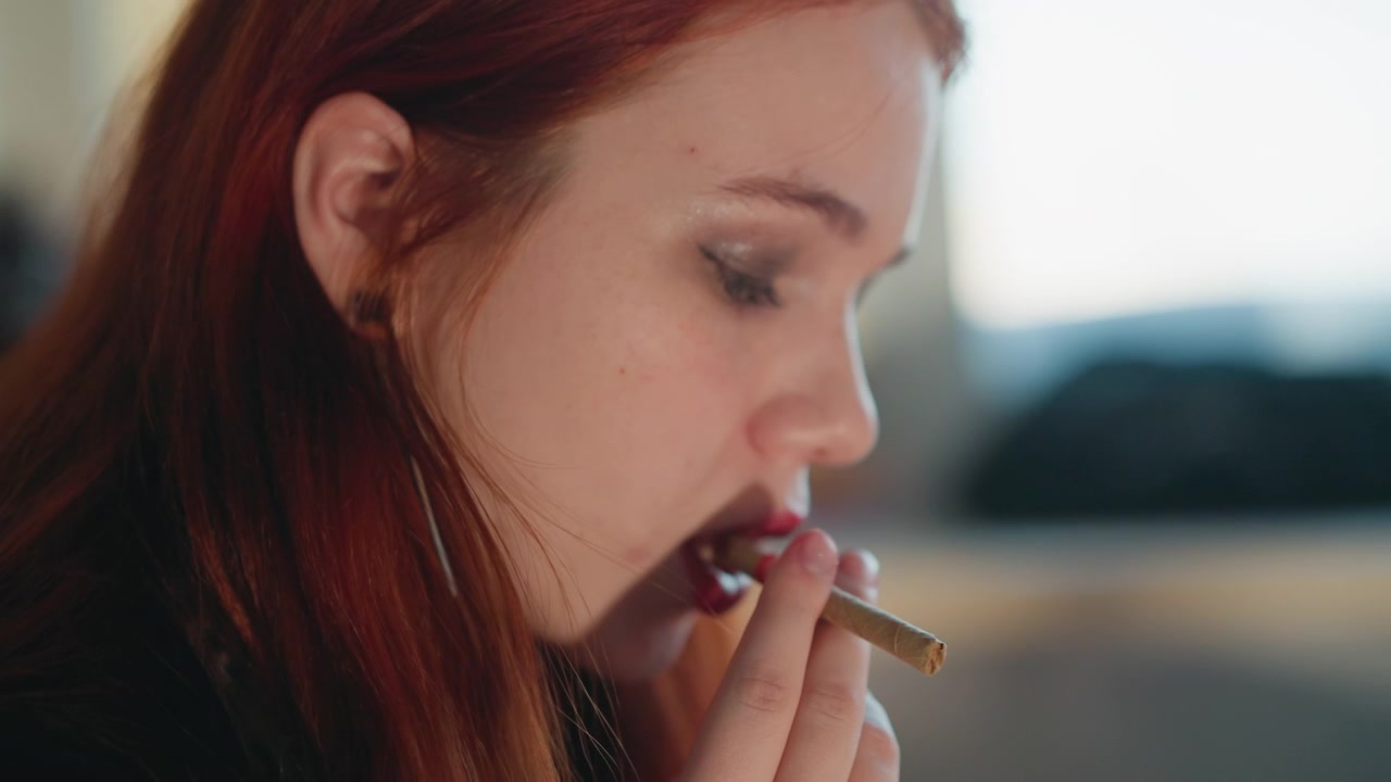 Clarividente pelirroja caucásica inhalando antes de una visión en suave perfil lateral, primer plano íntimo de la respiración ritual y cigarrillo cerca de los labios, suave contraluz natural, enfoque superficial cinematográfico, privado.