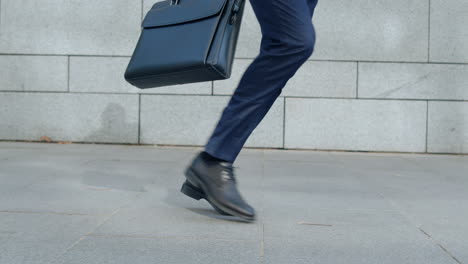 Businessman-feet-dancing-on-street-alone.-Employee-holding-briefcase-in-hand