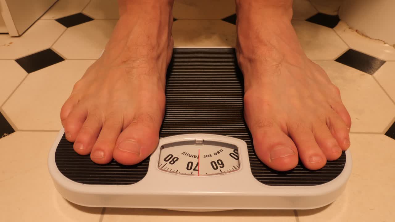 킬로그램 단위의 무게를 지닌 저울을 밟고 내리는 사람의 정면