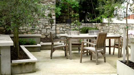 a quiet garden in old walls with a stylish table and chairs waiting for guests.