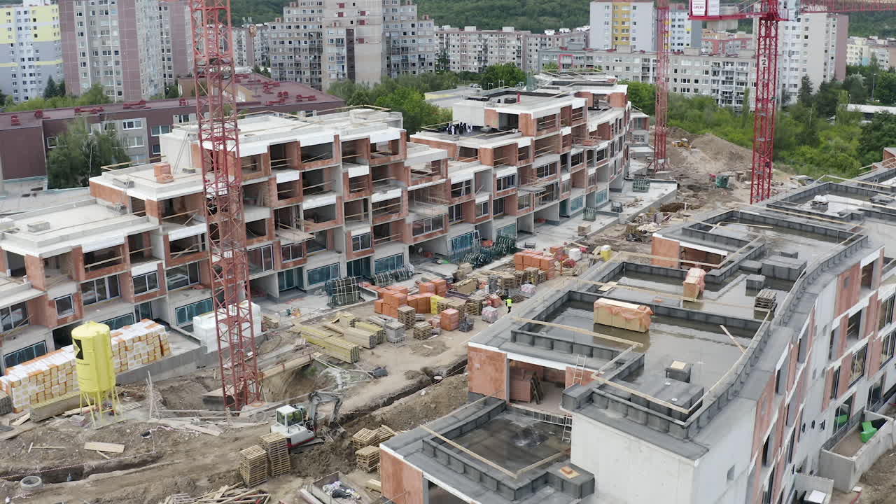vista aérea del sitio de construcción de apartamentos con grúas, material, ciudad