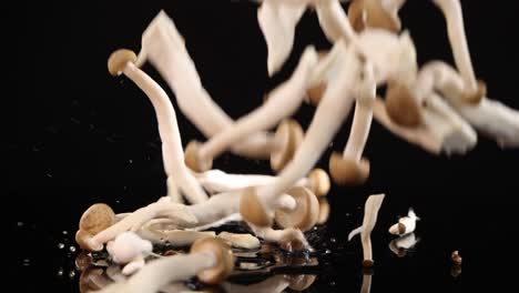 brown beech mushrooms drop in slow motion onto a glossy black surface, creating dynamic movement and scattering, with dramatic studio lighting and high contrast