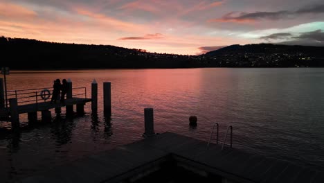 flying over silhouette of a dock during sunset at a lake in switzerland