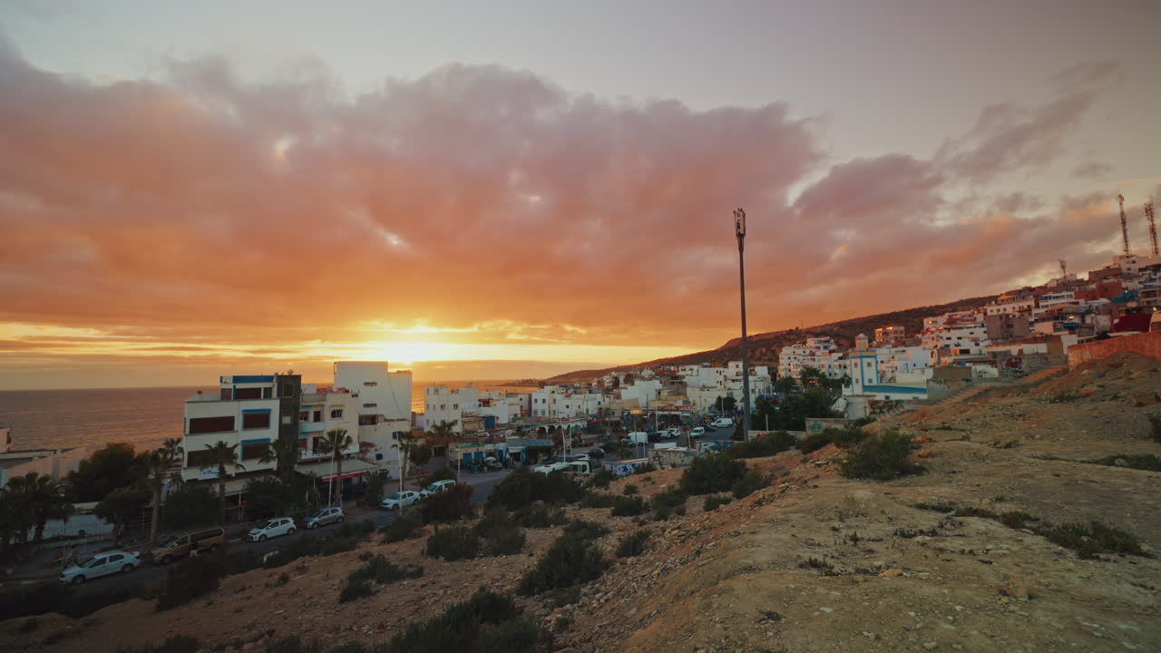 Panoramic view of the local town of Taghazout in Morocco at sunset. Warm dramatic sky, sunlight coming through the clouds.