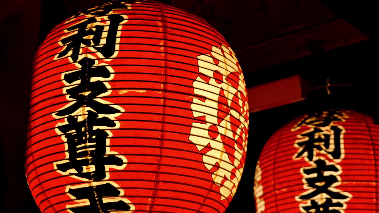 Softly glowing red lanterns hang from wooden beams in a tranquil Japanese temple, casting a warm and inviting light.