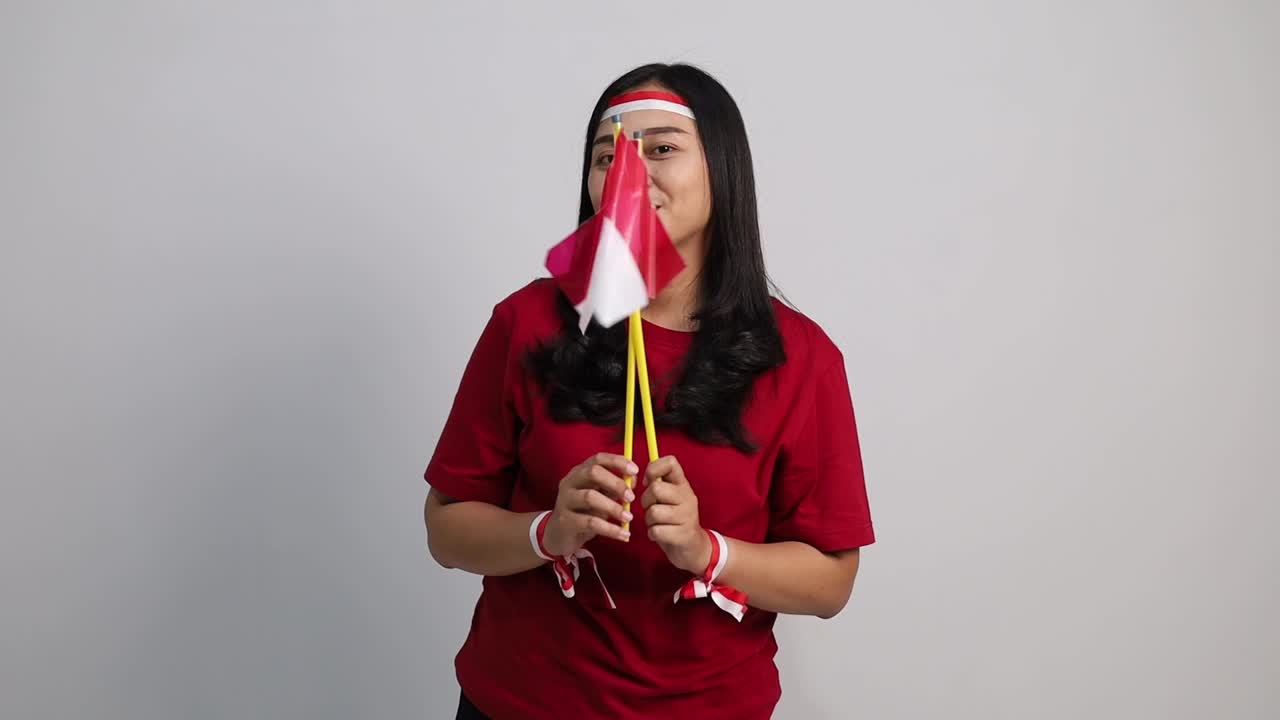 Indonesian woman standing holding red white flag to celebrates Indonesia independence day