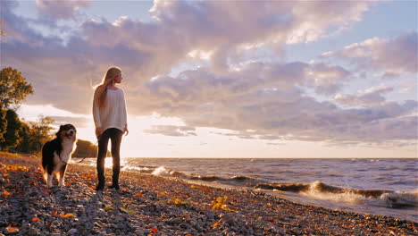 una mujer joven paseando a su perro al atardecer junto a un lago 3
