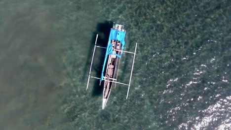 aerial view above a boat at a beach, in indonesia - rising, top down, drone shot