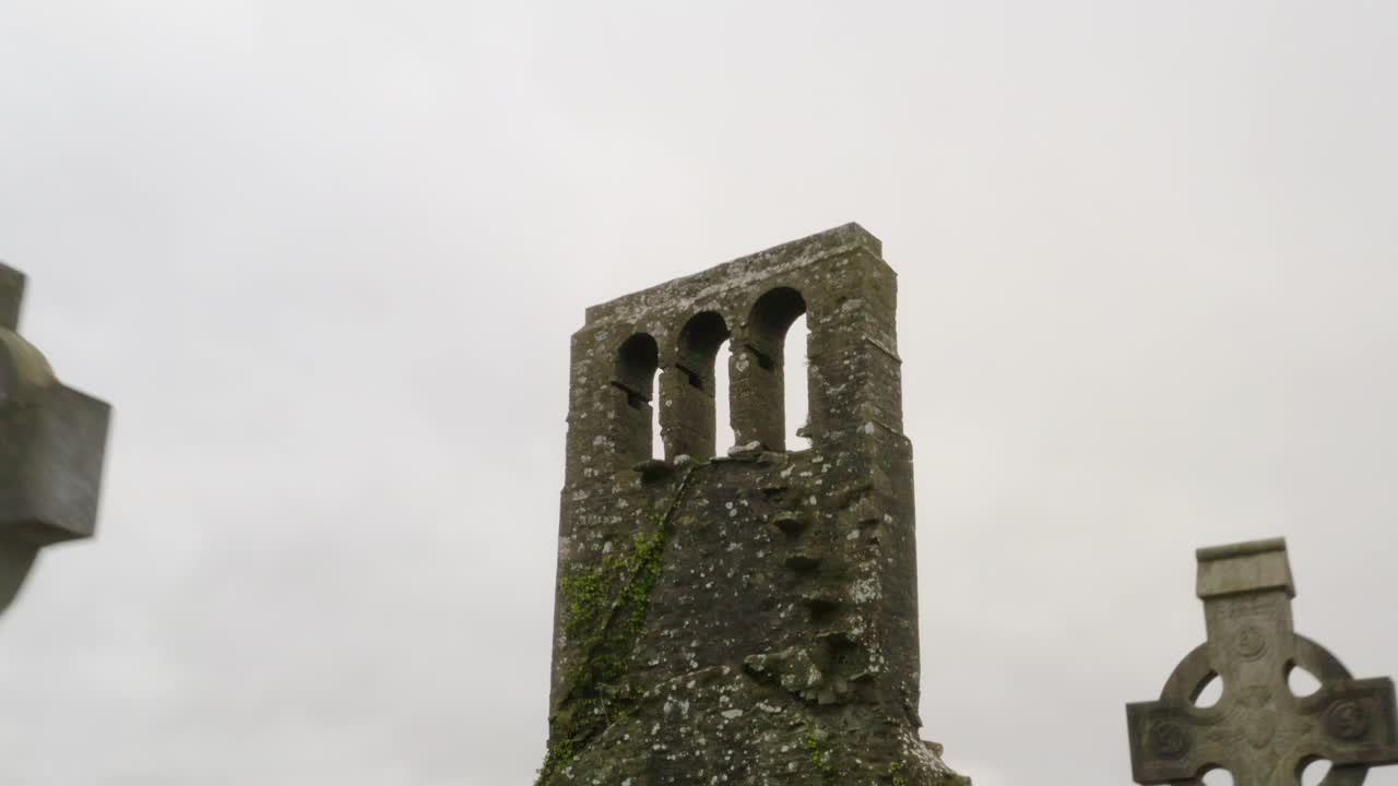 Moss lichen covered church tower and arch windows with eerie old graveyard headstones