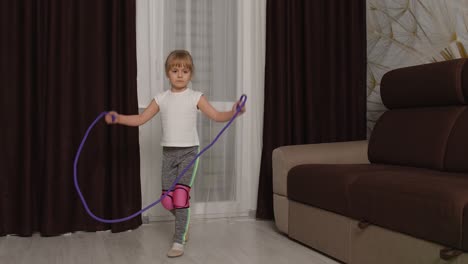 kid girl doing sport exercises, watching video online education lessons on laptop computer at home