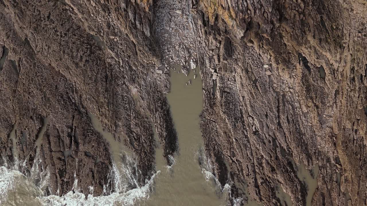 Aerial view featuring rocky terrains with white Mumbles Lighthouse near Swansea United Kingdom during noon.