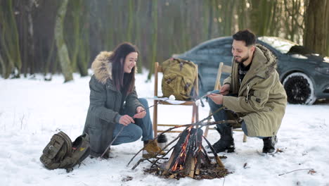 Caucasian couple camping in a snowed forest.