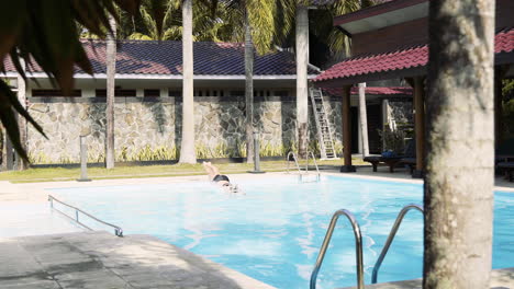 woman jumping in a pool at a tropical resort