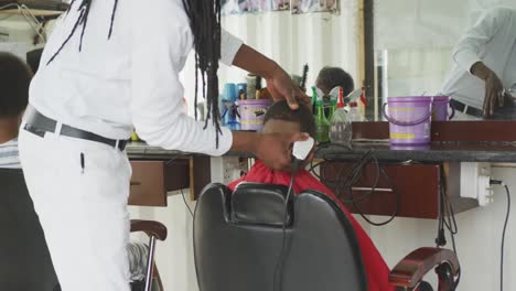 african man cutting african boy hair