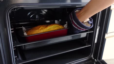 person taking a loaf of bread out of the oven