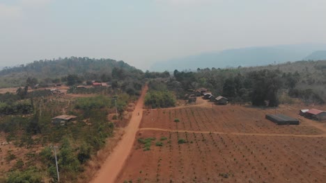 Wide-shot-of-rural-dusty-road-at-Laos-during-day-time,-aerial