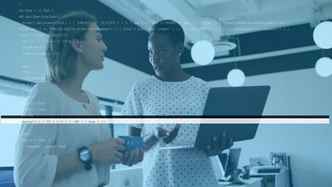 Two female colleagues discussing data on laptop in modern open-plan office, with animated charts