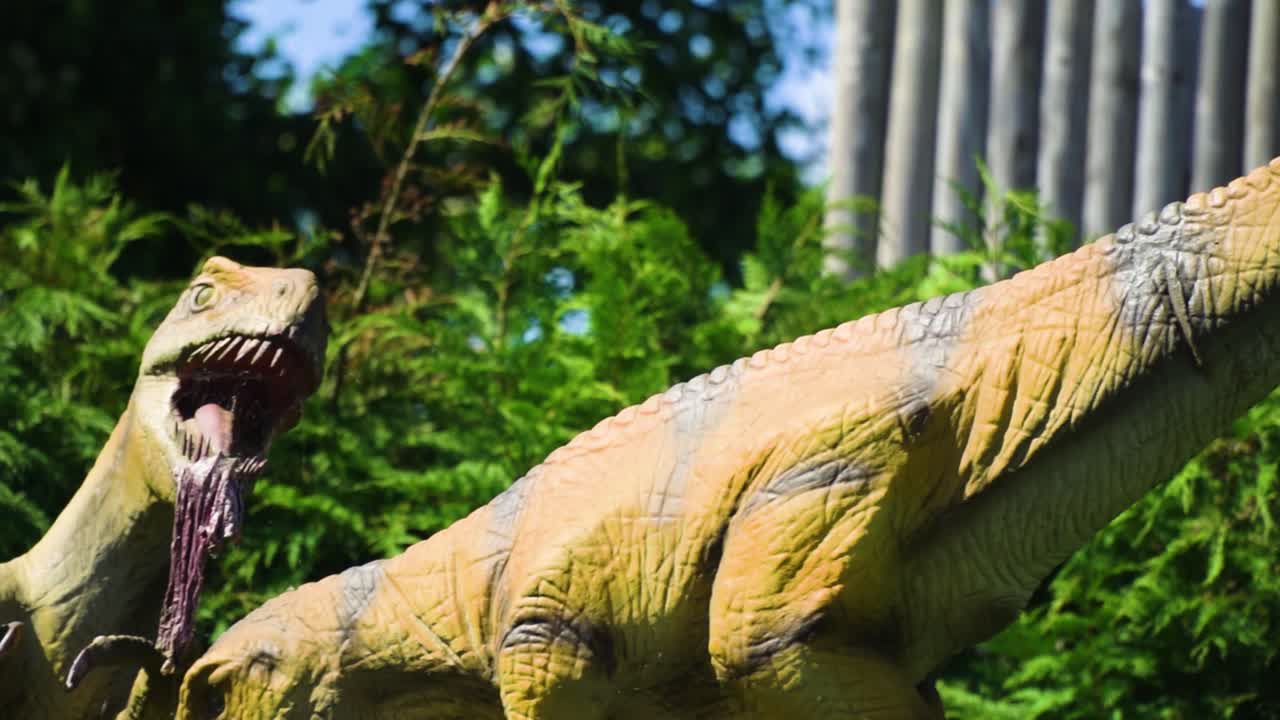 두 마리의 무서운 파충류 공룡이 입에 매달려 있는 크고 날카로운 이빨로 적대적인 갈색 피부 생생한 환경 슬로우 모션으로 먹이를 먹고 있습니다.