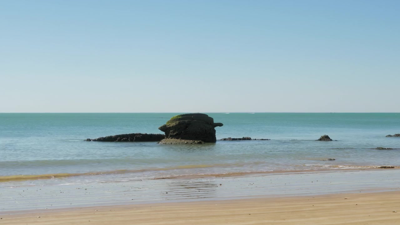 Timelapse at Playa Micaela, with clear blue sky and rocks on the ocean