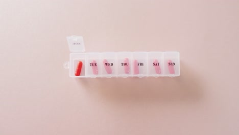video de pastillas rojas en la caja de pastillas semanal en fondo rosa con espacio para copiar.