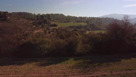 The-marganell-region-in-barcelona-spain-with-lush-green-fields-and-distant-mountains,-aerial-view