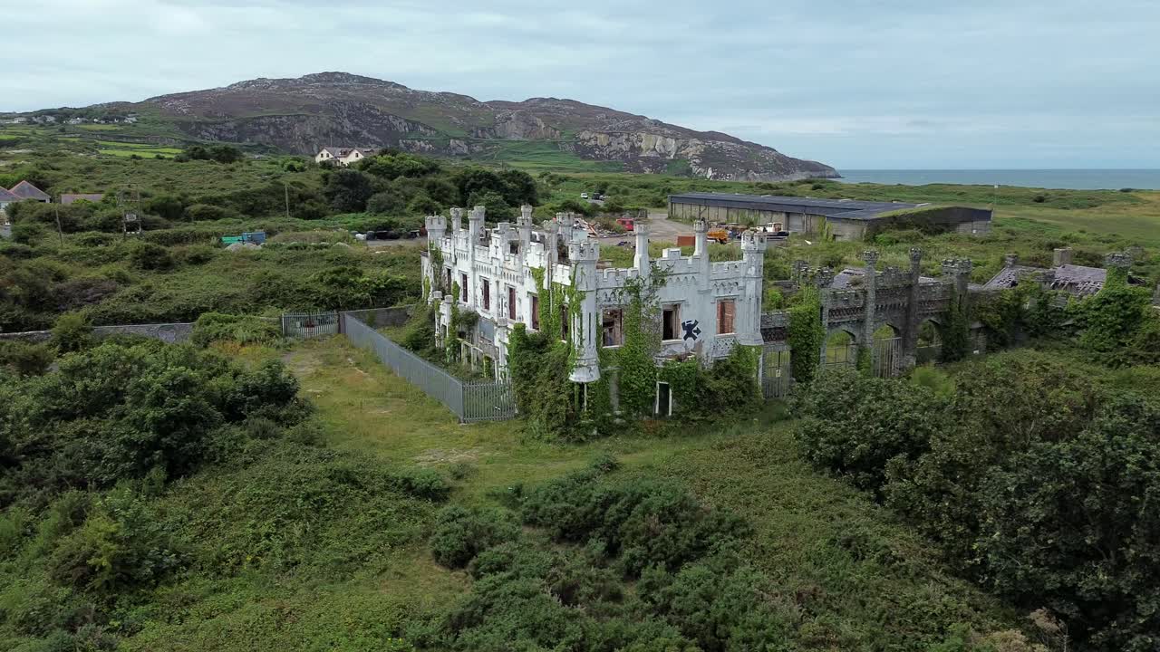 Uninhabited mental health hospital remains aerial view circling overgrown North Wales landmark