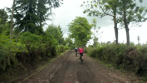 Marathon-athletes-cycling-on-a-dirt-road-with-mountain-bike-riding-uphill-very-heavy-workout-in-jungle-forest-Tanzania---4k