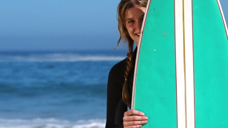 mujer en traje de baño escondiéndose detrás de una tabla de surf