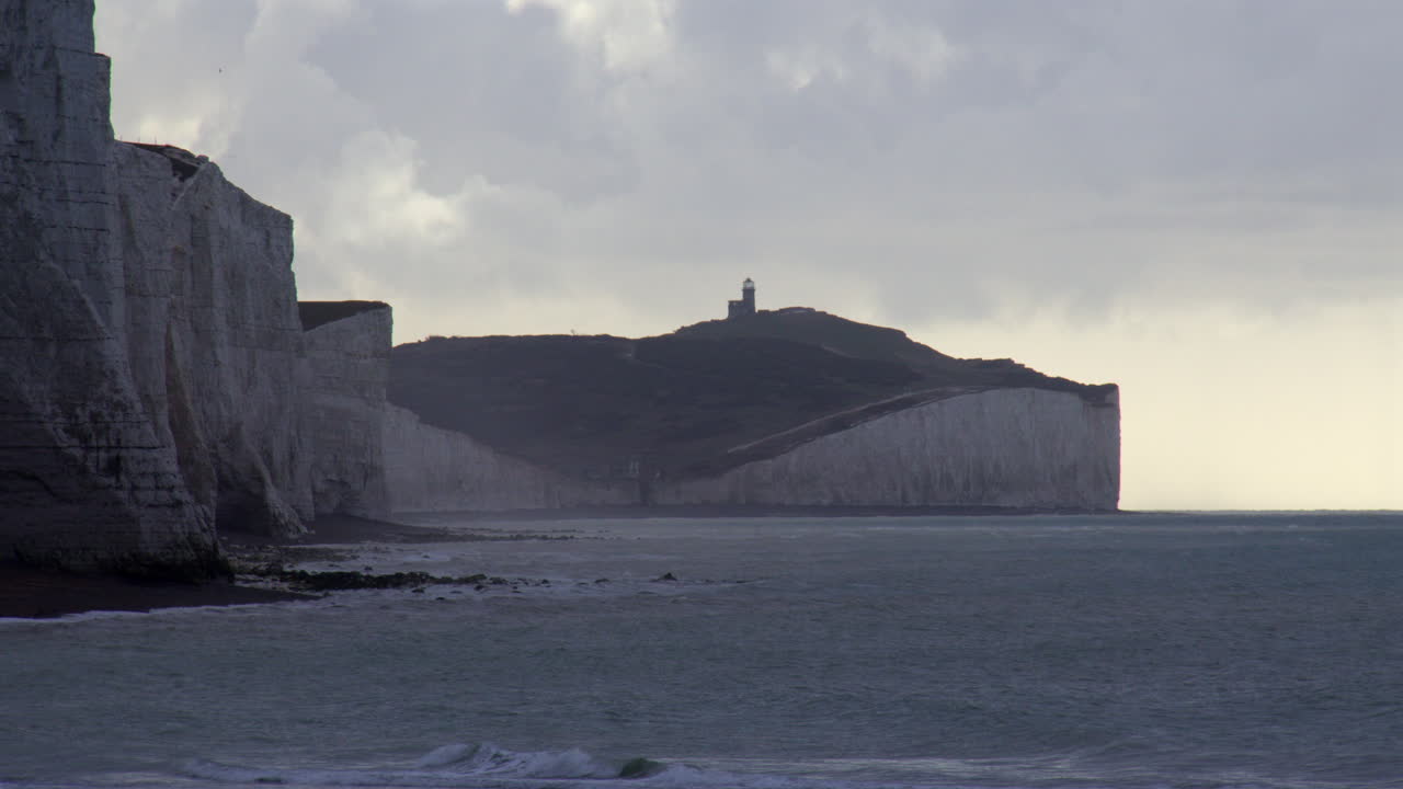 Campo lungo della scogliera delle Seven Sisters al mattino con il faro di Belle Tout sullo sfondo sulla spiaggia di Cuckmere Haven, vicino a Seaford Head.