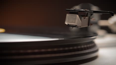 dropping stylus needle on vinyl record playing with disc rotating close up