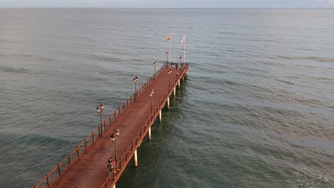 wooden jetty on the mediterranean sea with people walking on it