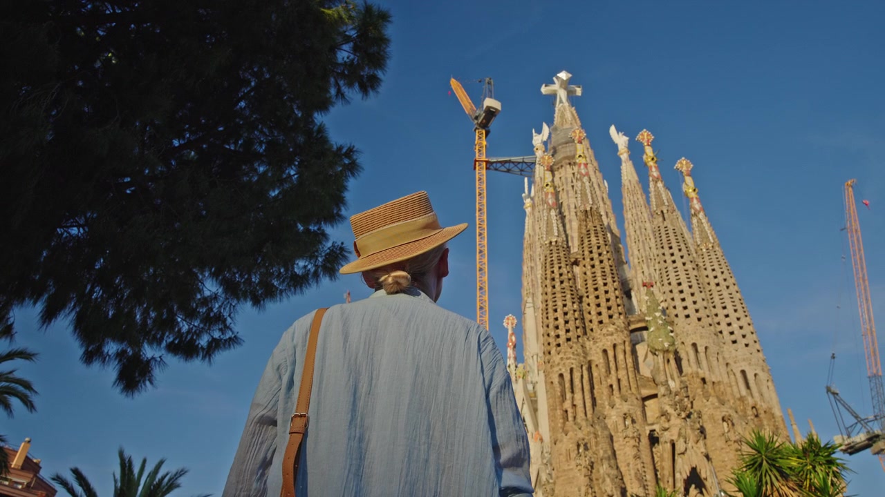 Turista con cappello di paglia che ammira la Sagrada Familia a Barcellona