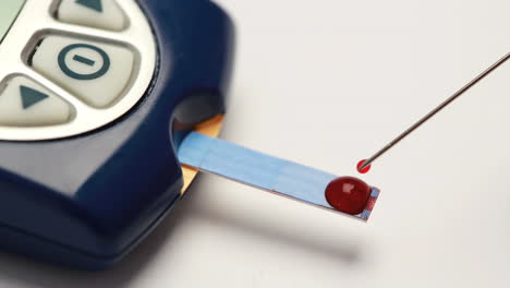 drop of blood syringed onto test strip of glucose monitor