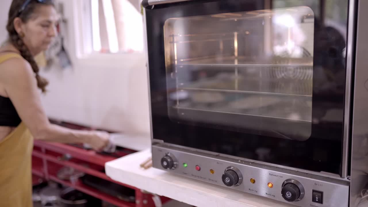 Donna che toglie una teglia calda dal forno.