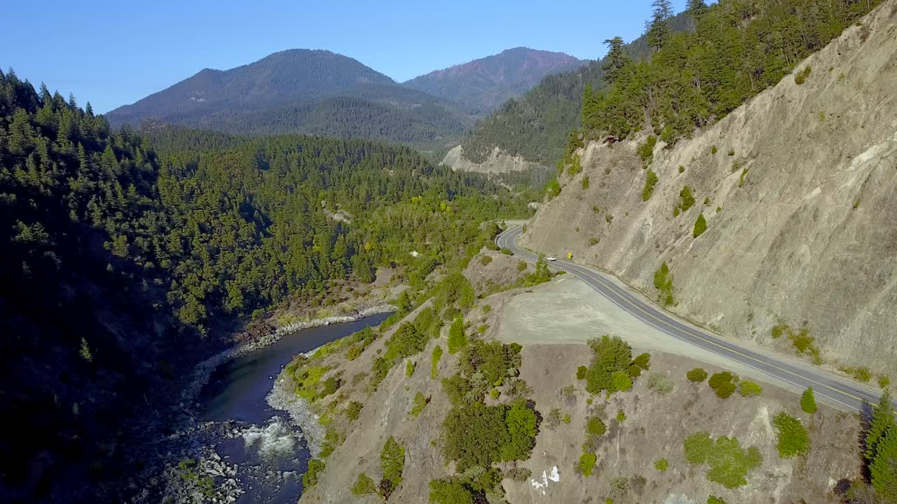An aerial view of cars moving down a remote road in the wilderness.