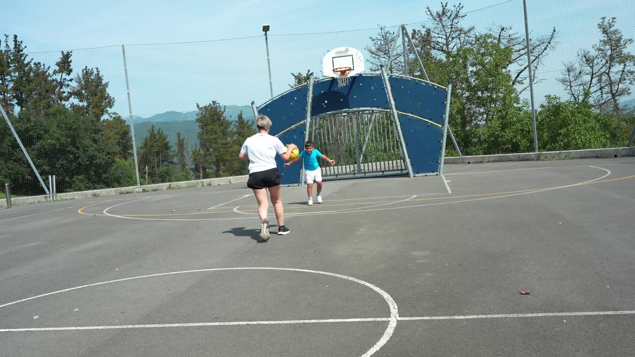 Donna e ragazzo giocano con la palla su un campo sportivo all'aperto