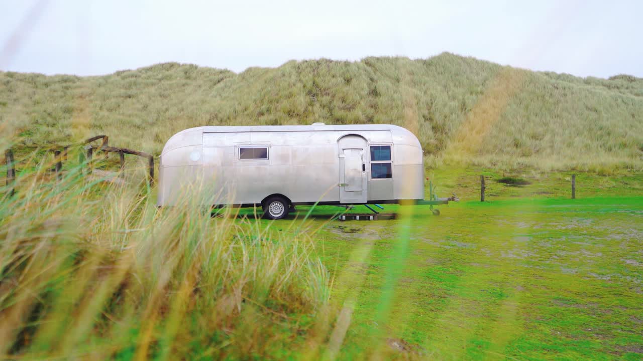 Trailer parked on a green meadow. Camper. Caravan. Motor home. Recreational vehicle. RV.