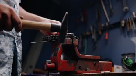 Close up shot of mechanic breaking a chain open with a hammer