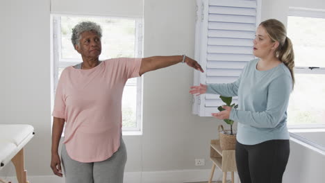 Caucasian-female-physiotherapist-with-senior-woman-exercising,-copy-space,-slow-motion