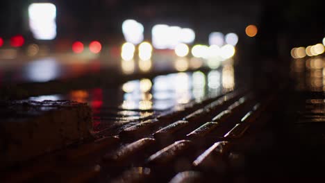 blurred background of city lights and cars traffic reflecting on wet road pavement at rainy night